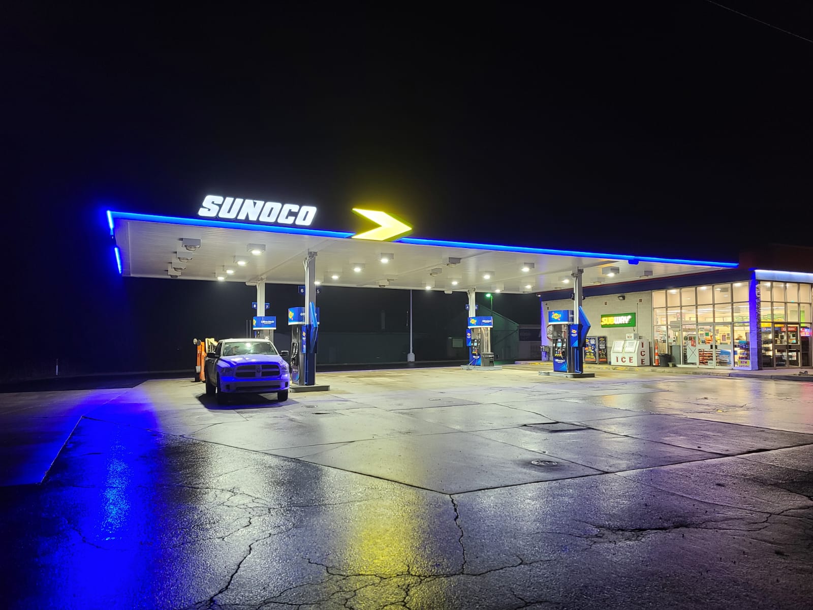 Sunoco gas station at night with lights, truck parked and convenience store